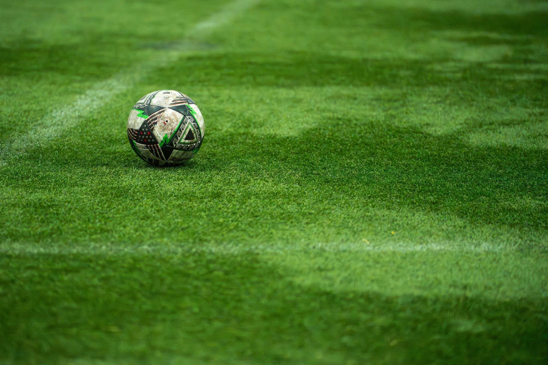 Balón de fútbol sobre el césped sintético de una cancha